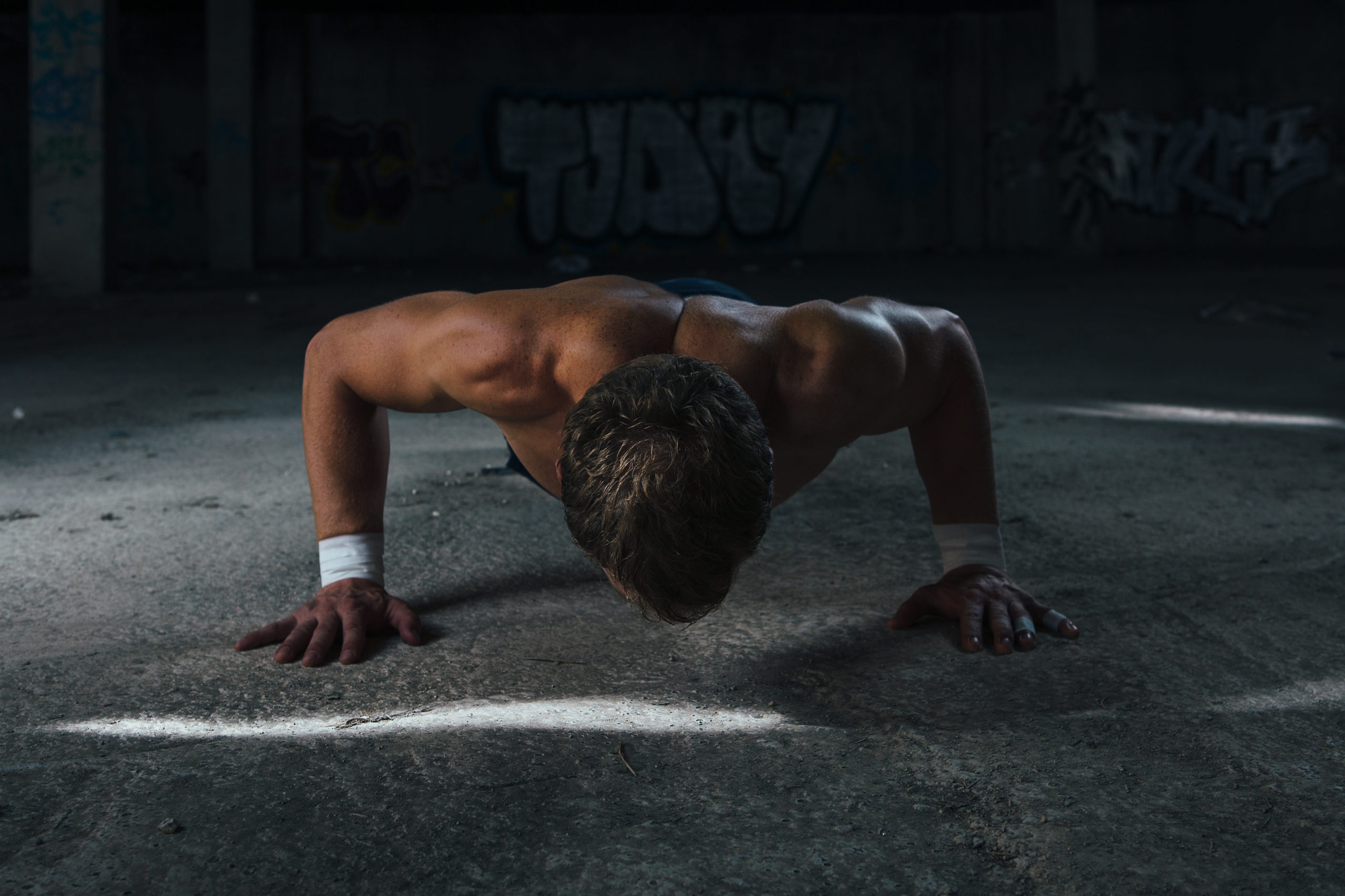 Muscle man looking down while doing push ups. Horizontal indoors shot